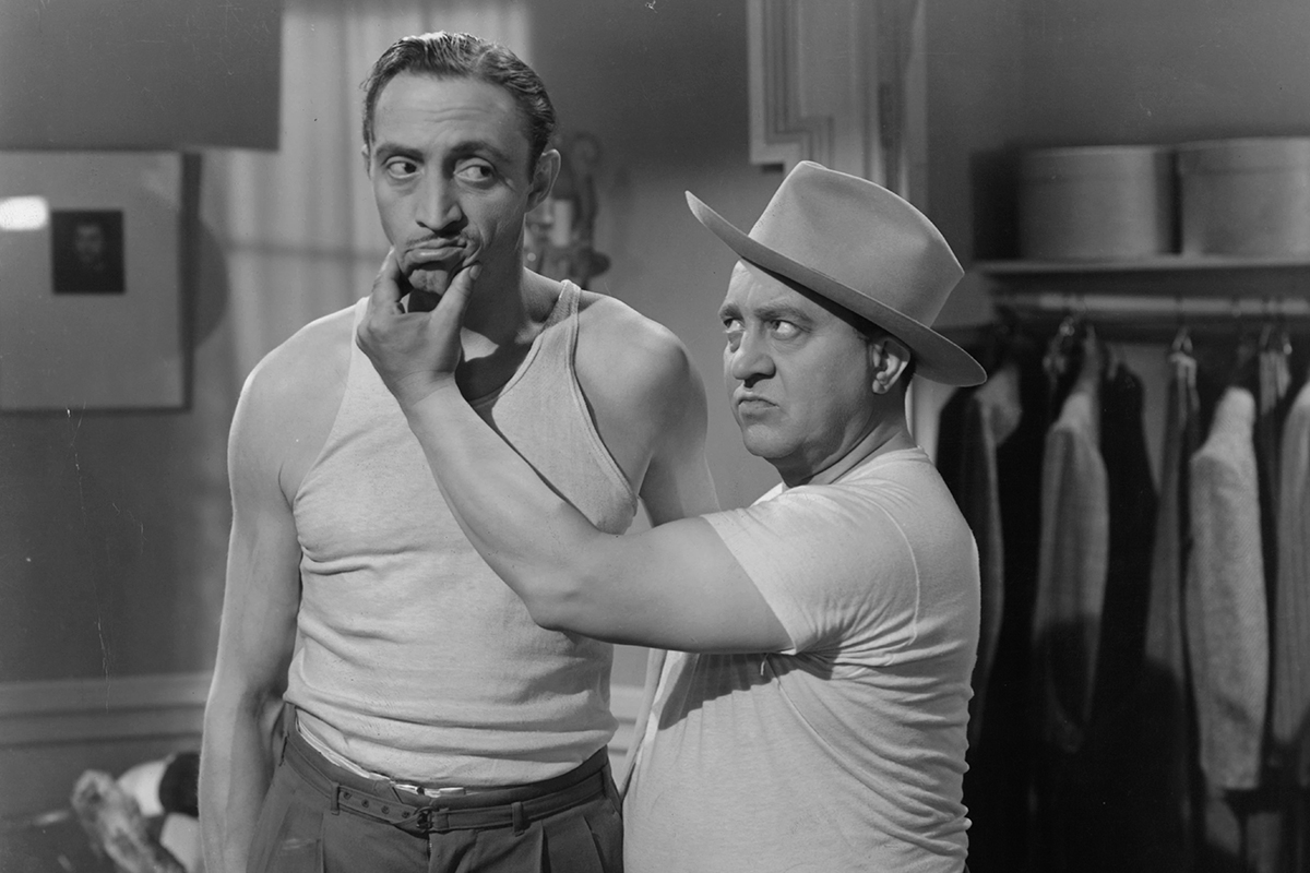 Mischa Auer cheeks are pinched by Chic Johnson in a scene from the film 'Hellzapoppin'', 1941. (Photo by Universal/Getty Images)