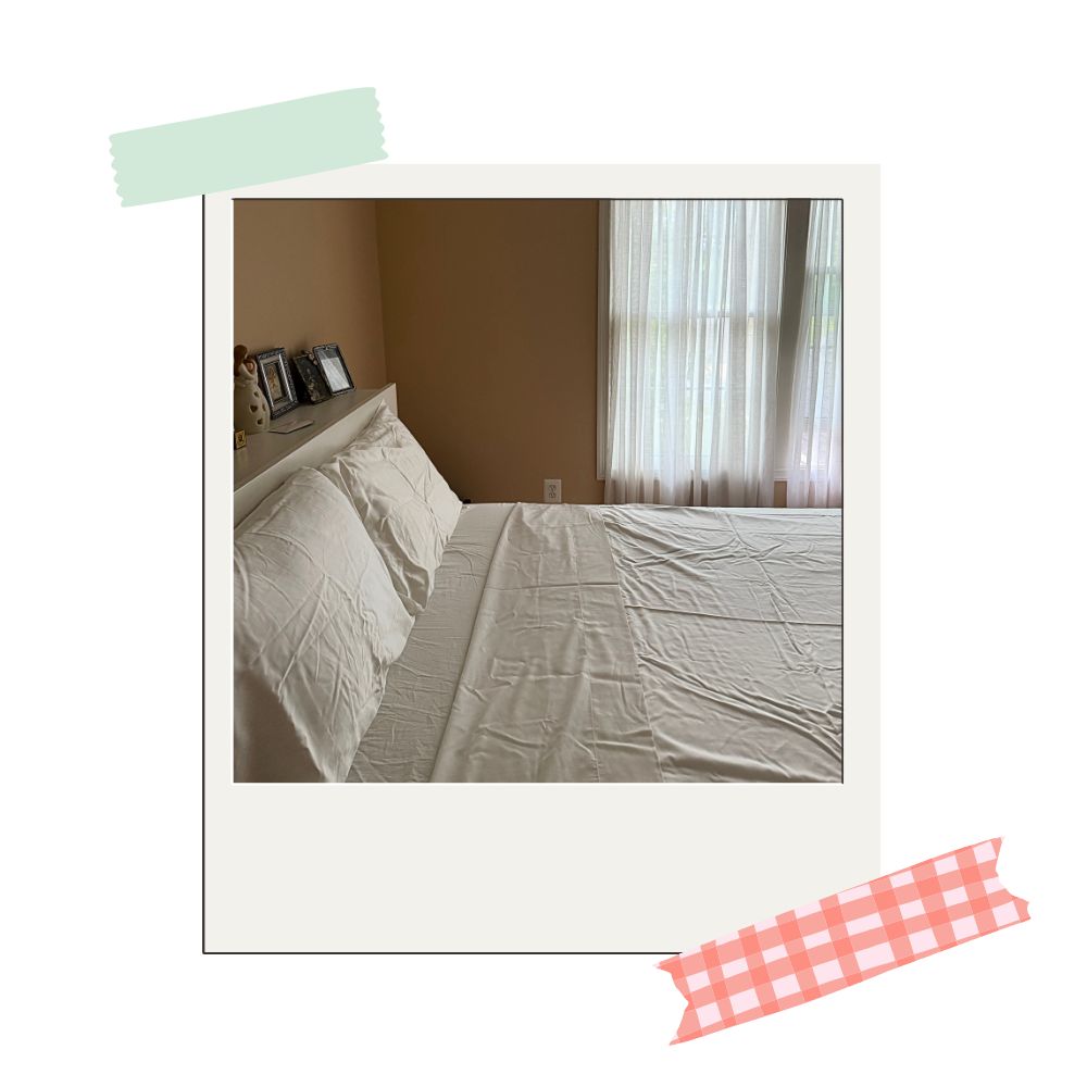 buffy sheet set in white colorway on a bed standing next to a window