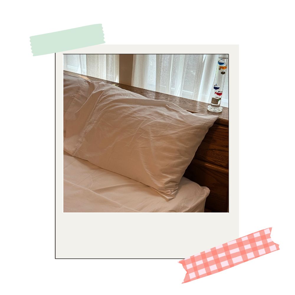saatva sateen sheet set in white on a bed standing right in front of a window