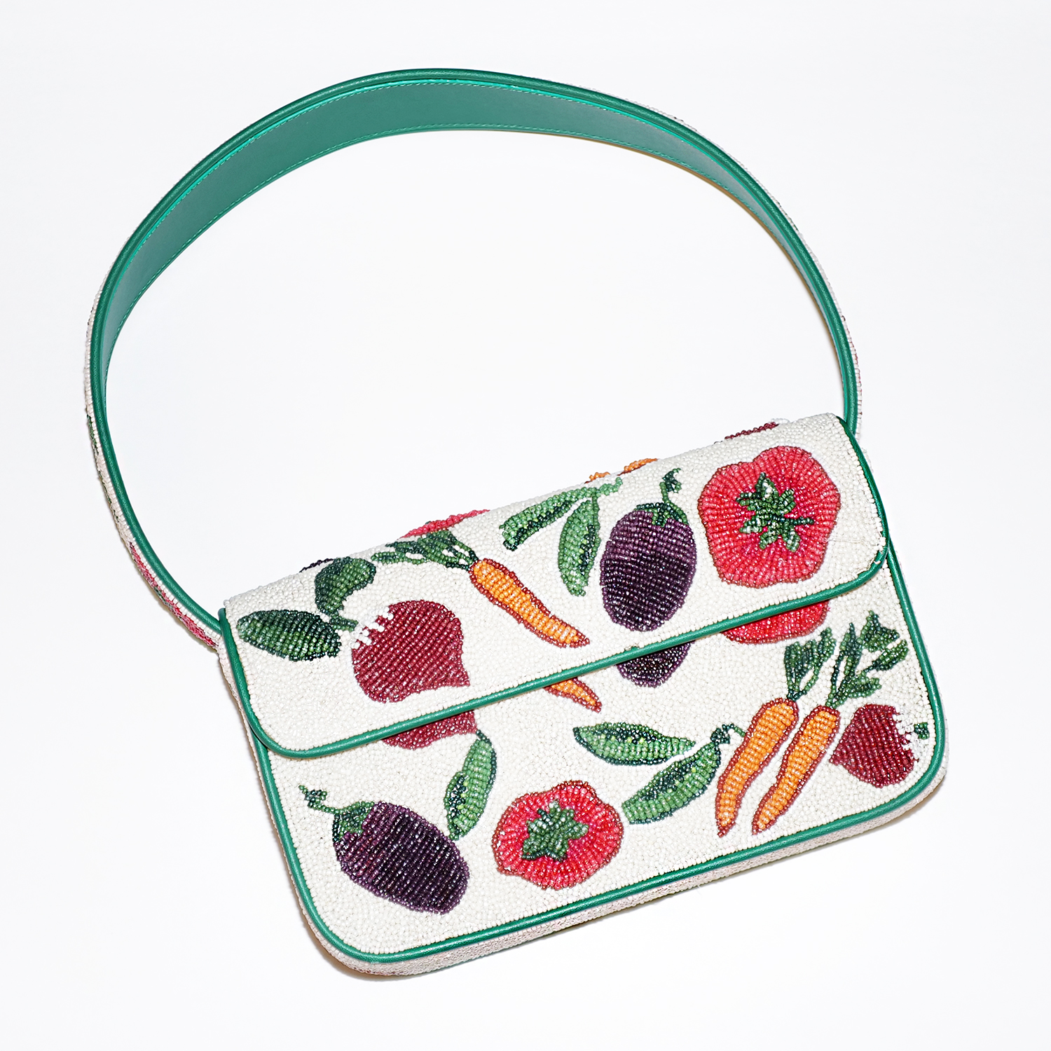 WWD shopping editors test Staud's Tommy Beaded Bag in a vegetable print on a white table