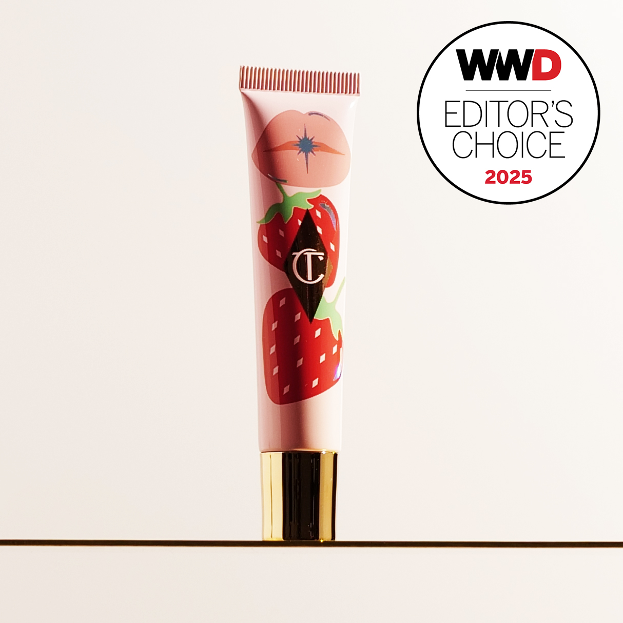 tube of Charlotte Tilbury's Unreal Lips Healthy Glow Nectar Oil in Strawberry Vanilla on gold testing stand