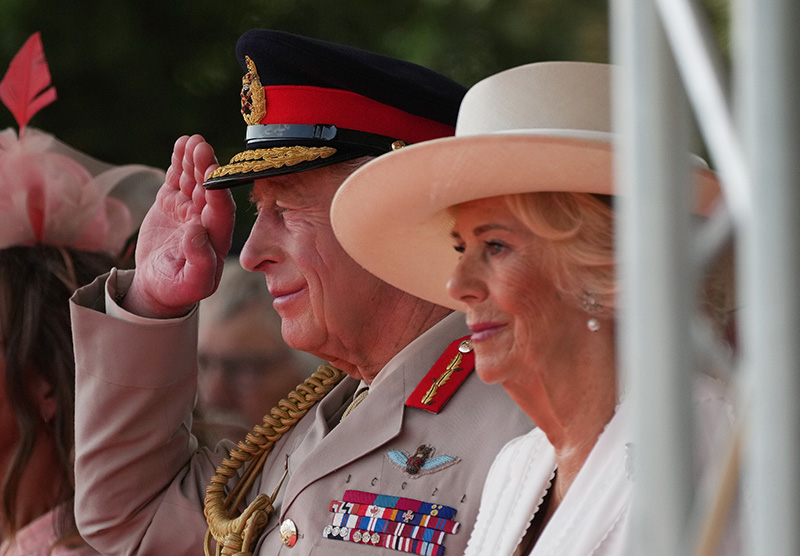 Queen Camilla wears white Dior dress and British bugle horn brooch for VJ Day celebration.