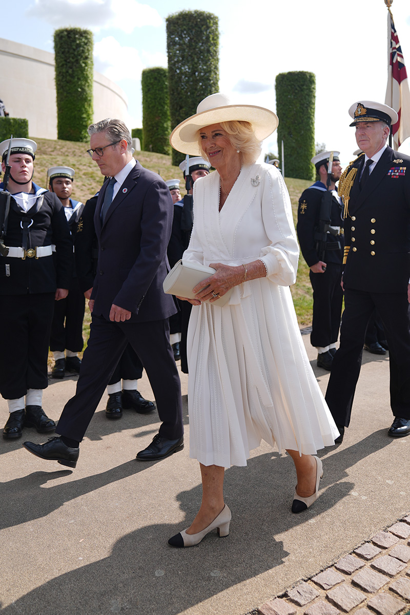 Queen Camilla wears white Dior dress and British bugle horn brooch for VJ Day celebration.
