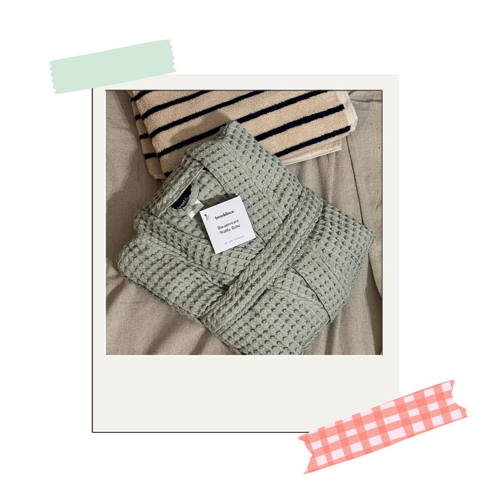 brooklinen's dreamweave waffle robe resting next to a striped brooklinen towel